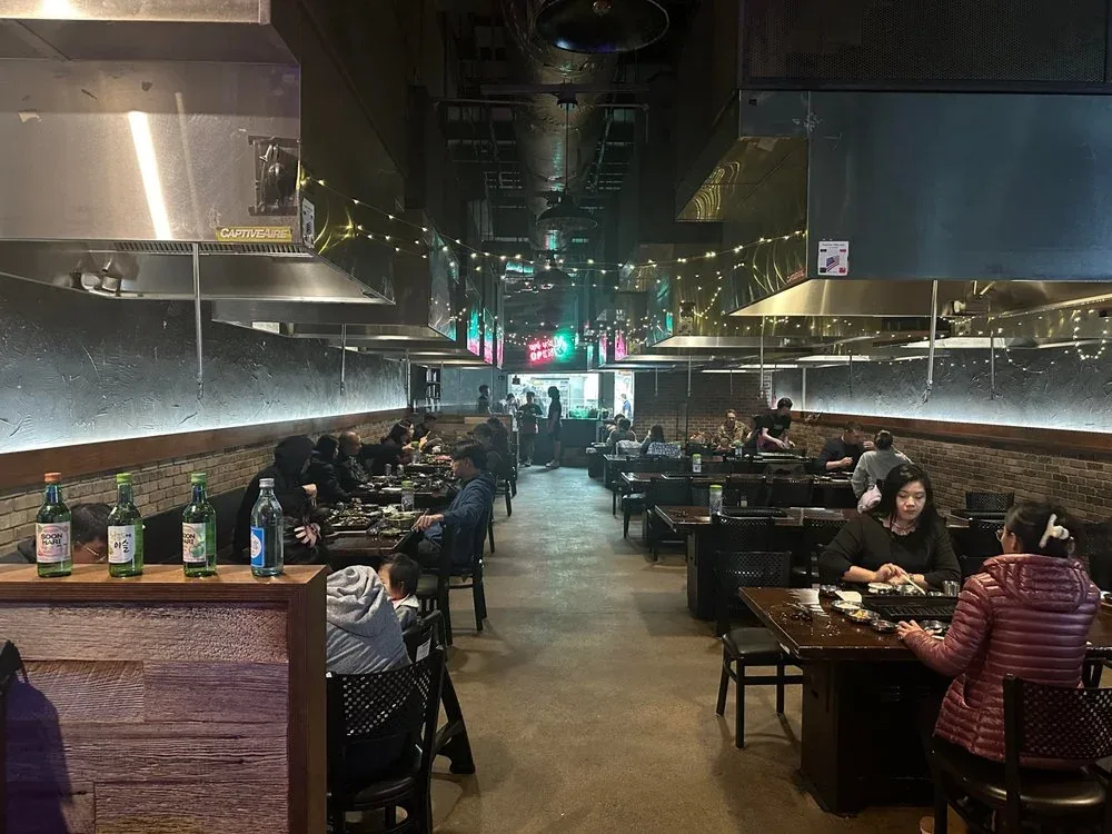 Inside Meokja Meokja: tables with built-in grills under string lights